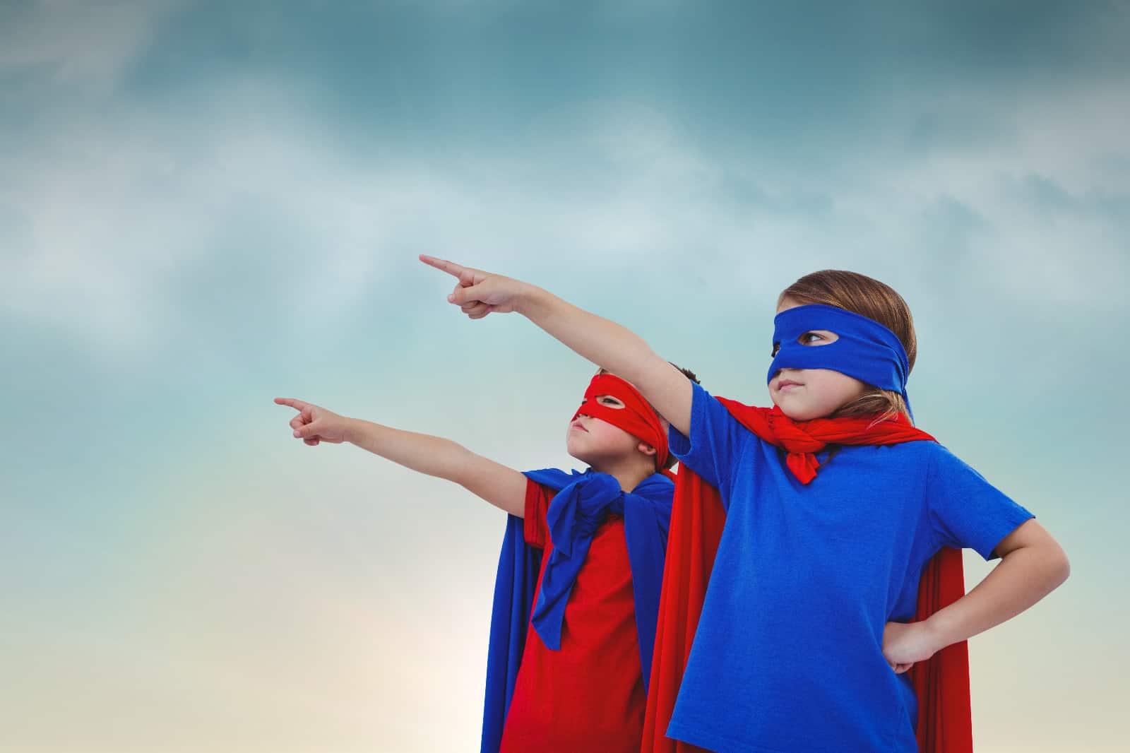 Kuvassa kaksi nuorta ihmistä pukeutuneena supersankareiksi osoittavat ylöspäin.